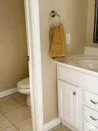 White vanity with integrated sink, brushed nickel hardware, and tile flooring