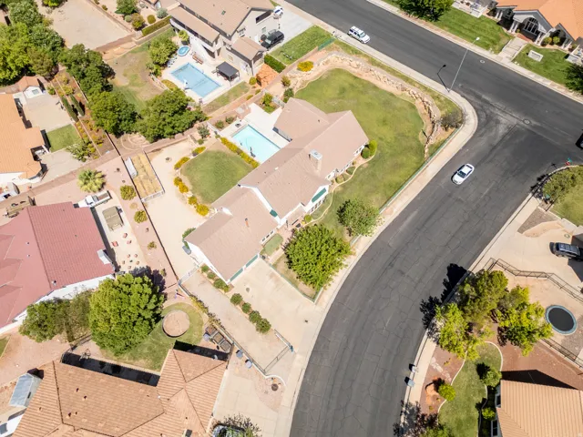 Expansive lot featuring a large in-ground swimming pool, manicured lawn, mature trees, and a paved driveway