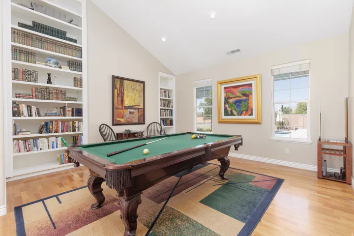 Vaulted ceiling with recessed lighting, built-in shelving, wood-finish flooring, and multiple windows