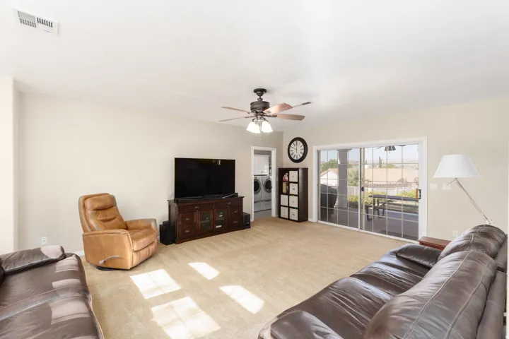 Spacious living room featuring tile flooring, ceiling fan with integrated lighting, and glass sliding doors opening to outdoor space