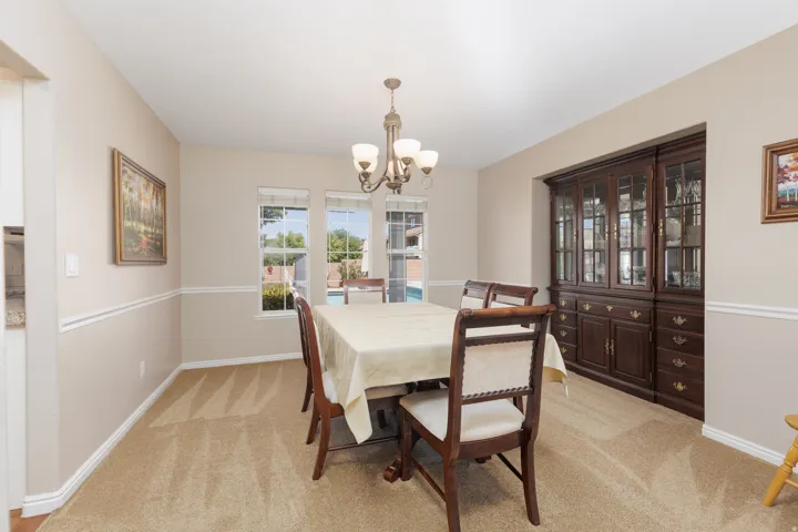 Built-in cabinetry with glass-front display, recessed lighting, chandelier lighting, and multiple windows
