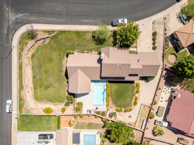 Expansive residential lot with a sizable lawn, a rectangular swimming pool, and a gravel driveway