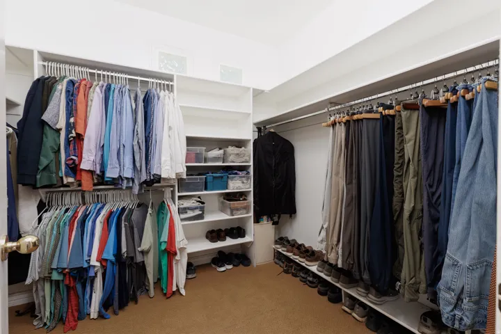 Integrated shelving system with multiple hanging rods, dedicated shoe storage, and overhead transom windows providing natural light