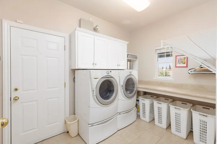 Built-in cabinetry, dual washer and dryer appliances, ample countertop space, window with natural light, and tile flooring