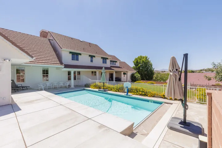 Sparkling resort-style swimming pool with sun deck featuring stamped concrete decking and integrated umbrella station