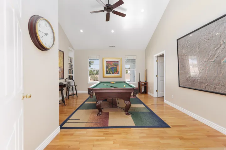 Spacious recreation room featuring wood-finish flooring, vaulted ceilings with ceiling fan, recessed lighting, and a pool table