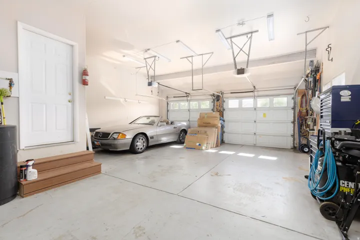 Spacious garage featuring a concrete floor, two white panel garage doors with windows, and overhead lighting