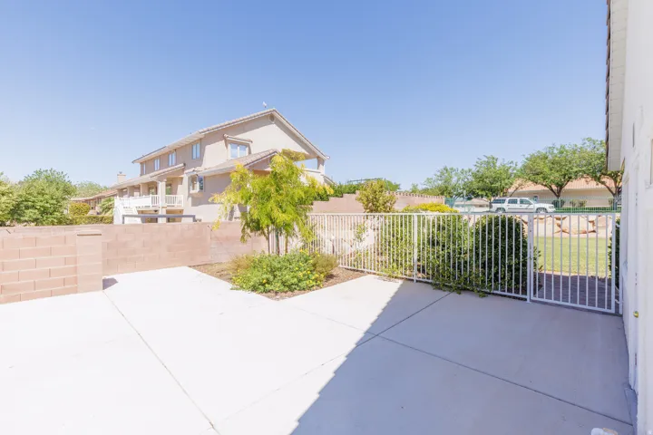 Paved patio area, white metal fencing, brick retaining wall, mature landscaping