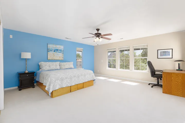 Recessed lighting, ceiling fan with light fixture, light-toned wall finishes, three large windows, and carpet flooring