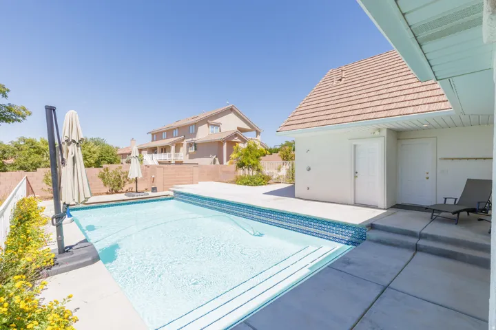 Outdoor swimming pool with integrated steps, mosaic tile detailing, and surrounding concrete decking