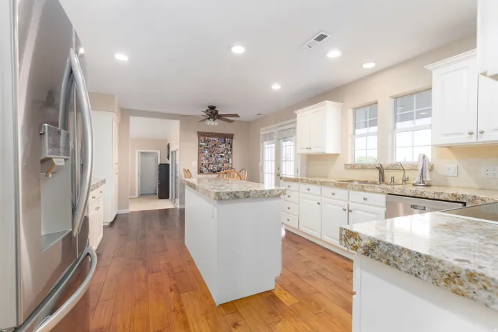 Kitchen featuring wood-finish flooring, white cabinetry, granite countertops, and stainless steel appliances