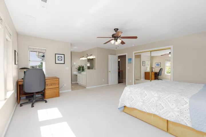Recessed lighting, ceiling fan, mirrored closet doors, and an attached vanity with double sinks