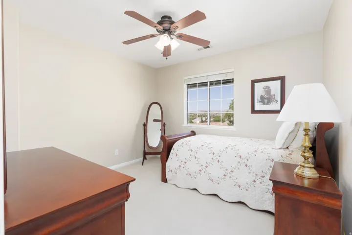 Neutral wall color with plush carpeting, ceiling fan with integrated lighting, and a window providing natural light