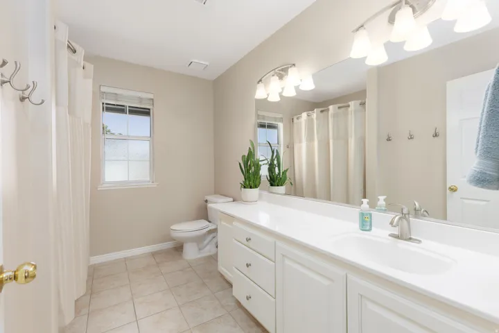 Spa-inspired primary bathroom featuring a double vanity with white cabinetry, white quartz countertop, and polished nickel fixtures