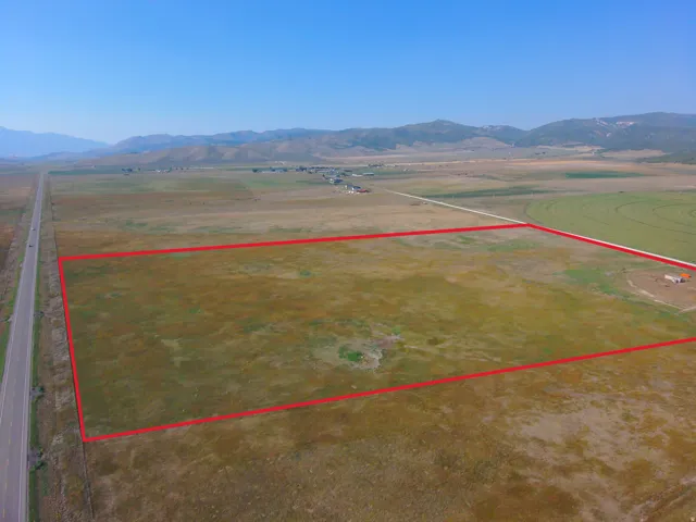 Expansive open land bordered by a paved roadway and distant mountains