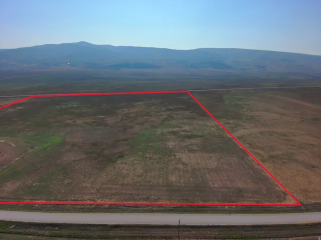 Expansive land parcel with natural terrain and a distant mountain range backdrop