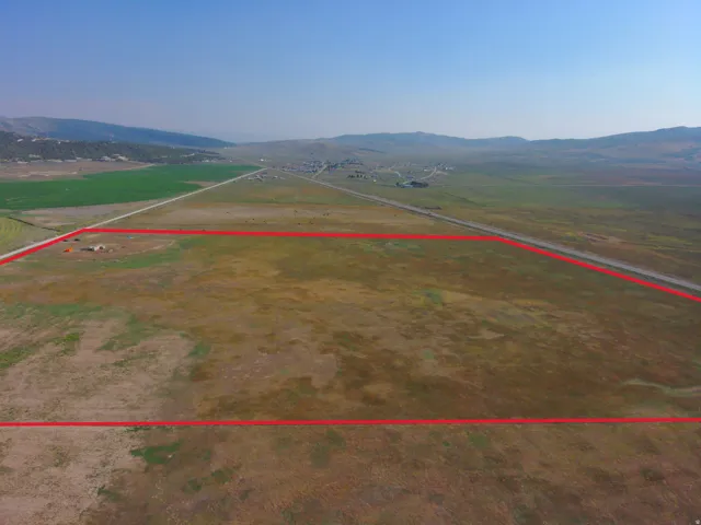 Expansive land parcel featuring clear boundaries, direct road frontage, and a distant mountain backdrop