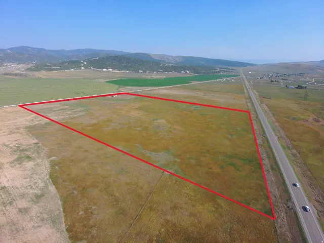 Expansive acreage featuring a perimeter outline, a paved road, and distant mountain topography