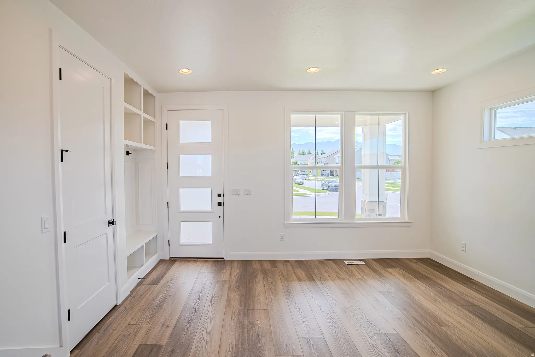 Wood-finish flooring, recessed lighting, and white built-in storage with a bench
