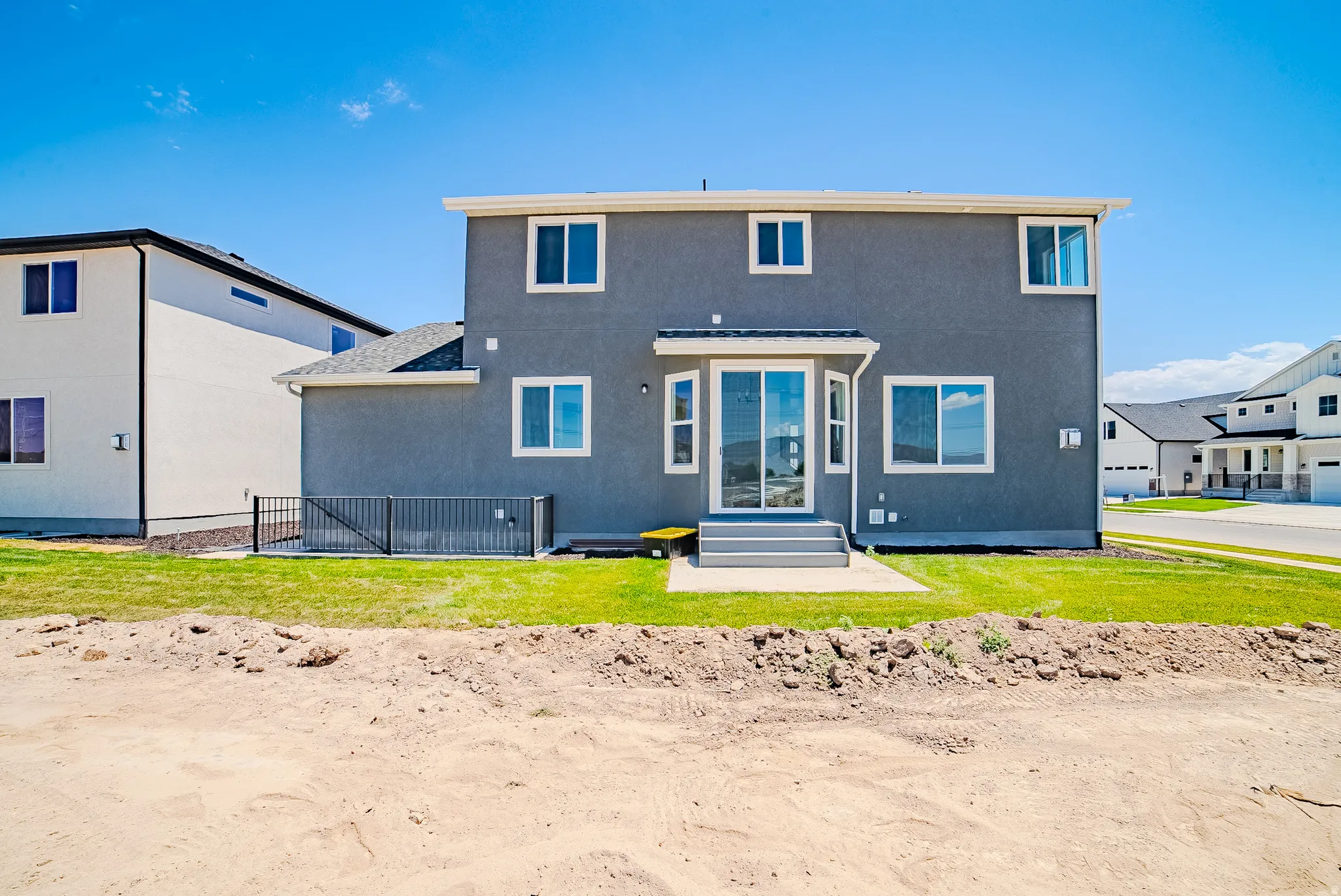 Two-story stucco exterior with white trim, a ground-level concrete patio, and a sliding glass door