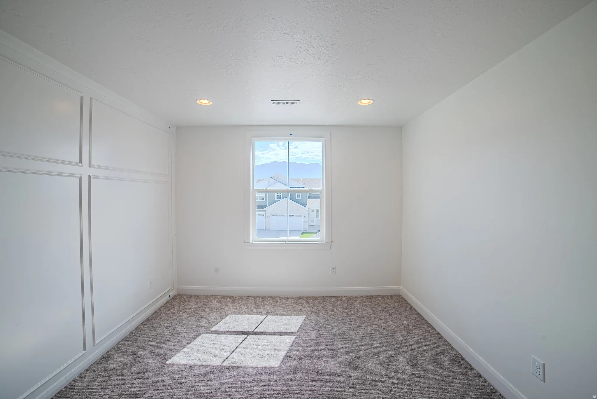 Crisp white walls, recessed ceiling lighting, and a single window offering a clear exterior