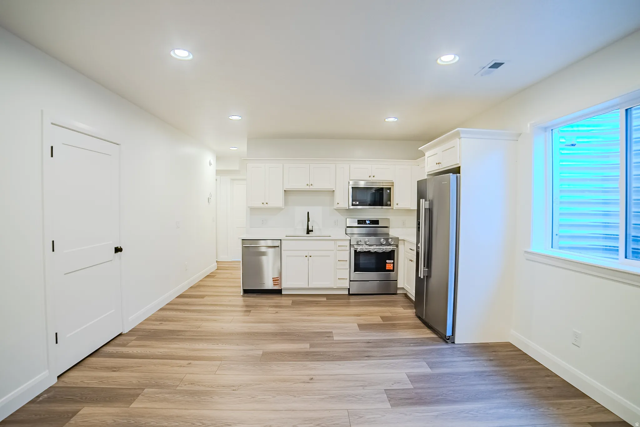 Open concept kitchen with white cabinetry and stainless steel appliances