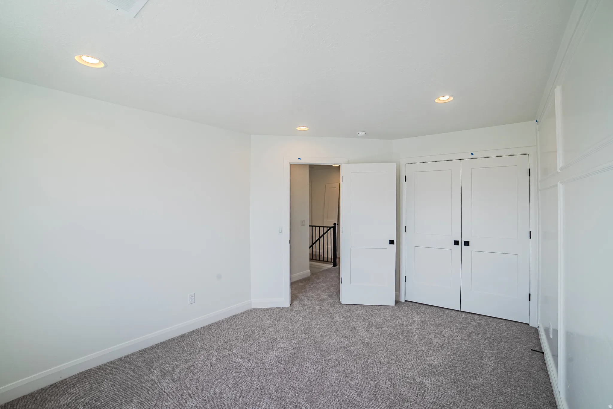 Recessed lighting, white paneled doors, carpeted flooring, and a white interior