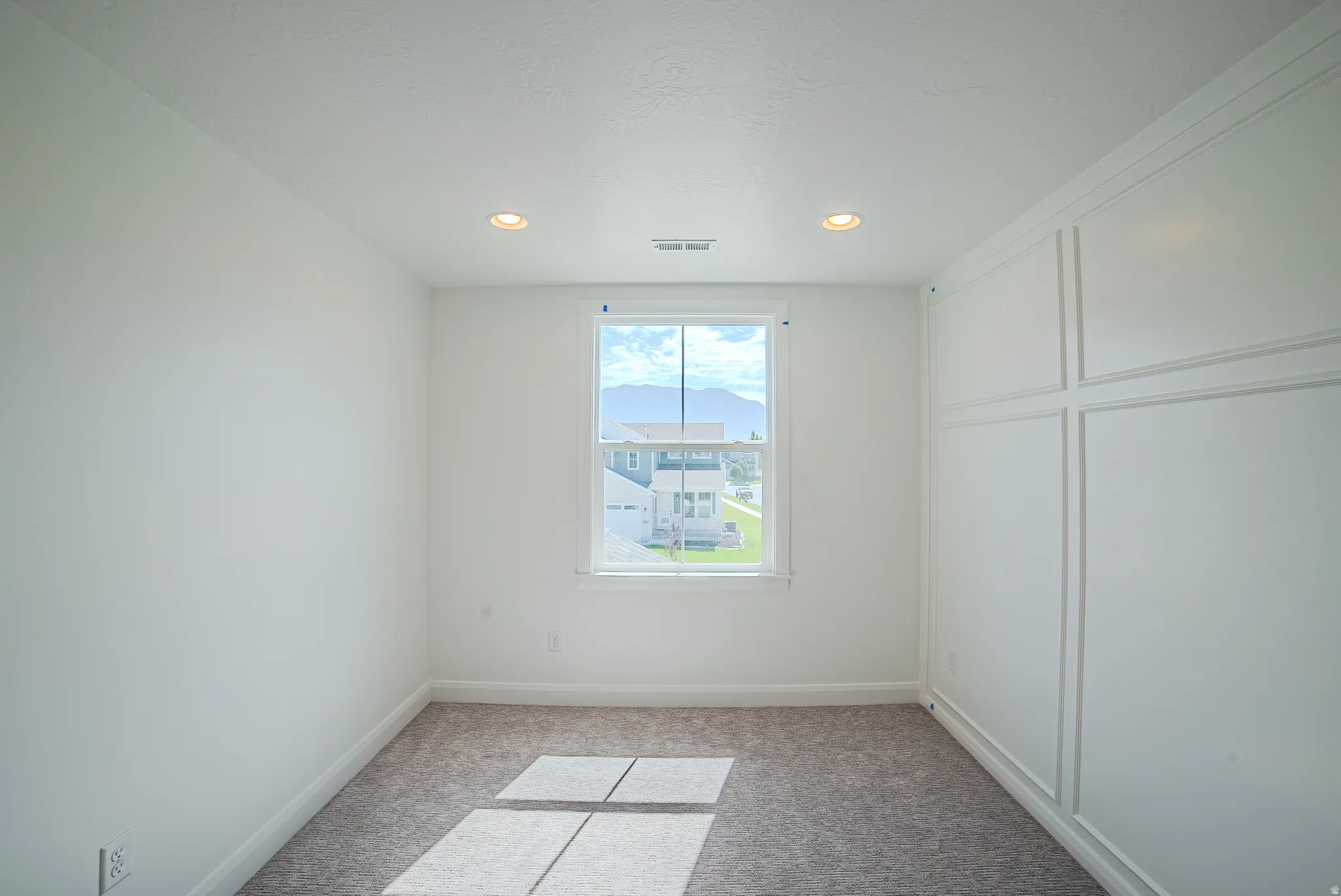 Recessed lighting, window with white trim, wall paneling, and carpeted flooring