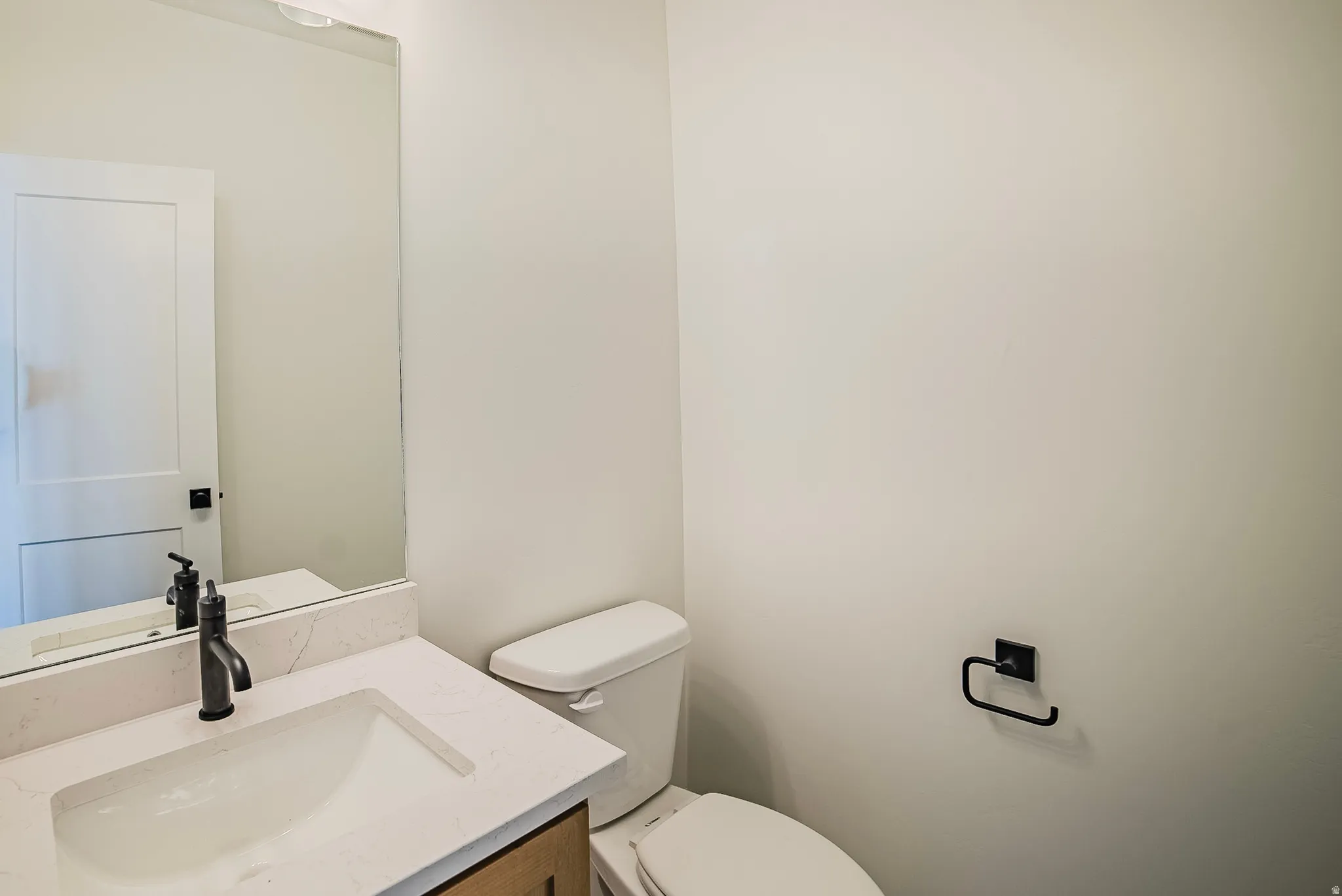 White vanity with an integrated sink, quartz countertop, and black matte faucet