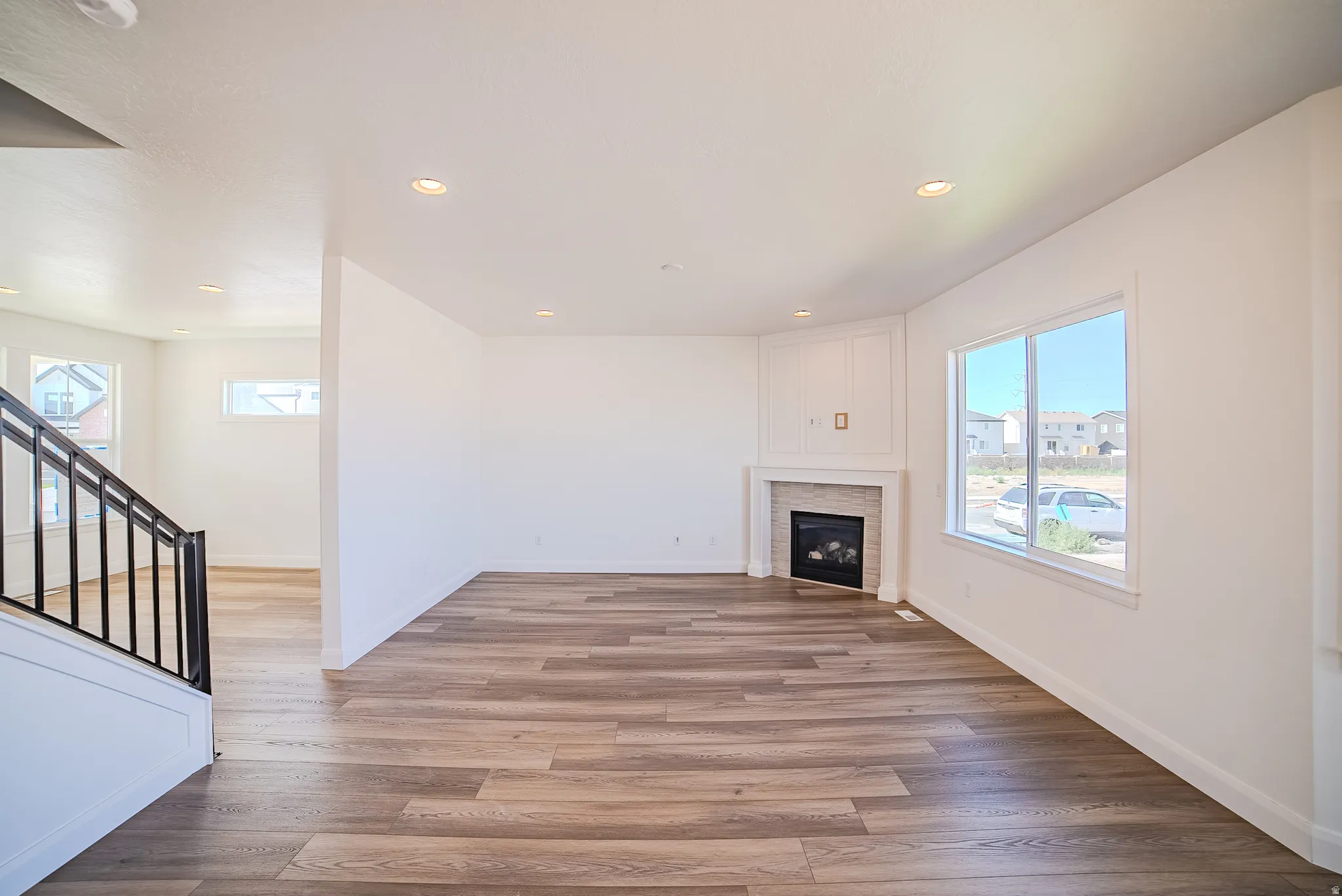 Wood-finish flooring throughout, recessed lighting, and a corner fireplace with a stone-tile surround