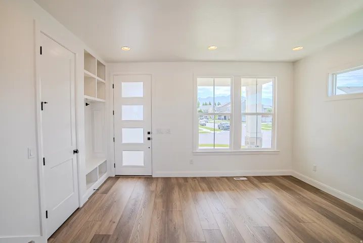 Wood-finish flooring, recessed lighting, and white built-in storage with a bench