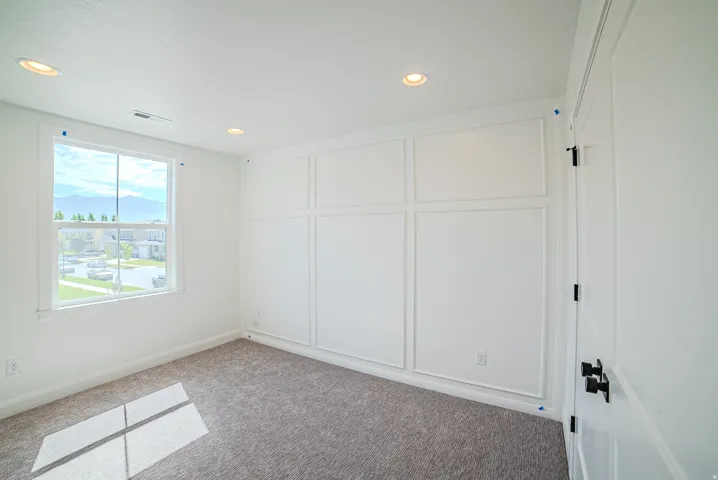 Board and batten accent wall, recessed lighting, double-hung window, white interior door with matte black hardware, and gray carpeting