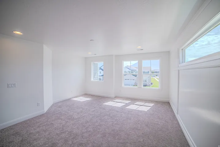 Plush carpet flooring, multiple windows, recessed lighting, and white trim