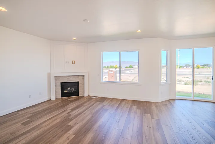 Wood-finish flooring, recessed lighting, and a fireplace with a tiled surround