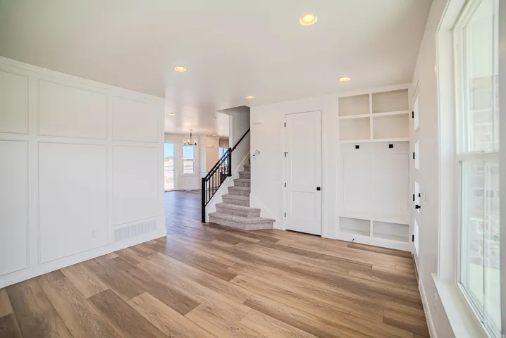 Wood-finish flooring throughout, board and batten wall detailing, built-in storage bench, recessed lighting, and a staircase with metal balusters