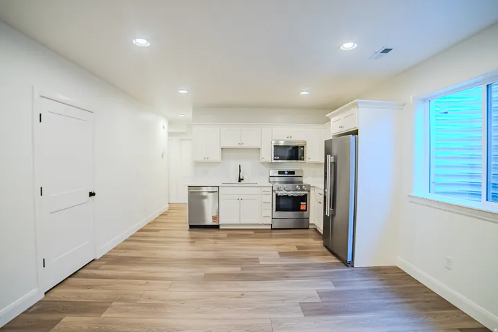 Open concept kitchen with white cabinetry and stainless steel appliances