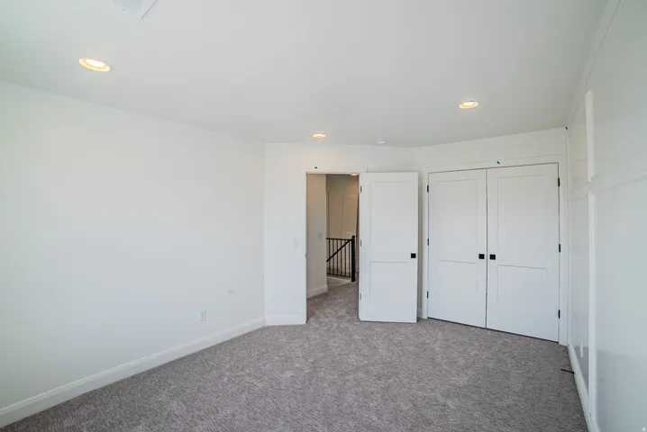 Recessed lighting, white paneled doors, carpeted flooring, and a white interior