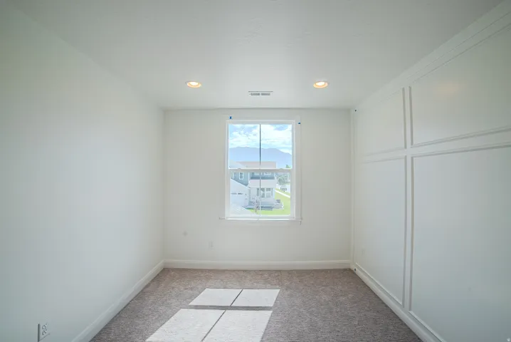 Recessed lighting, window with white trim, wall paneling, and carpeted flooring