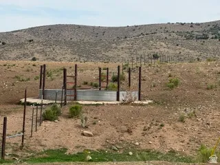 Additional contentThe photo shows a rural/undeveloped property with sparse vegetation, wooden fence posts, and what appears to be a concrete foundation or pad structure