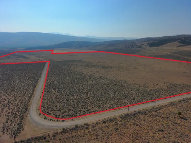 Expansive land parcel featuring a gravel road, distant mountain range, and varied low-lying vegetation