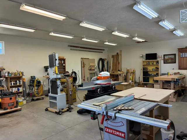 1040 Sq. Ft. Woodworking shop with overhead fluorescent light fixtures and a concrete floor