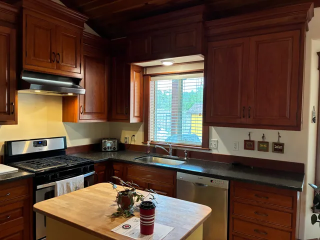 Kitchen featuring wood cabinetry, dark countertops, a stainless steel gas range, and a stainless steel dishwasher