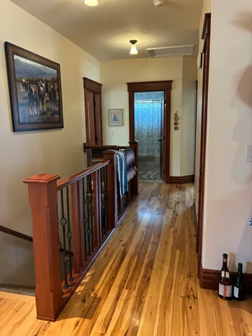Wood-finish flooring, staircase with wrought iron spindles, and wood trim detailing throughout