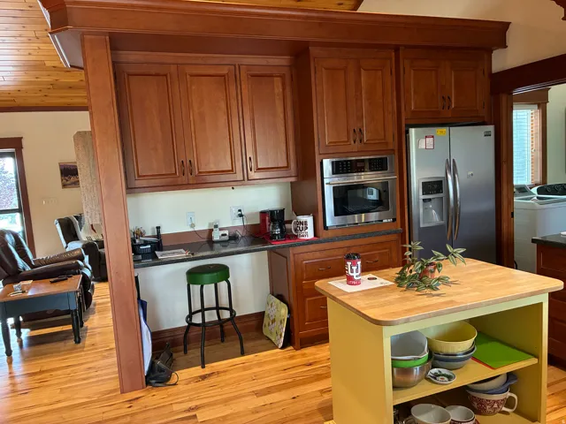 Wood-finish flooring, built-in cabinetry, stainless steel appliances, dark countertop, and a wood ceiling
