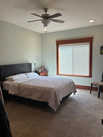Ceiling fan with integrated lighting, recessed lighting, window with wood trim, and wall-to-wall carpeting