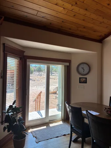 Wood-finish flooring with a multi-pane sliding glass door and an adjacent bay window