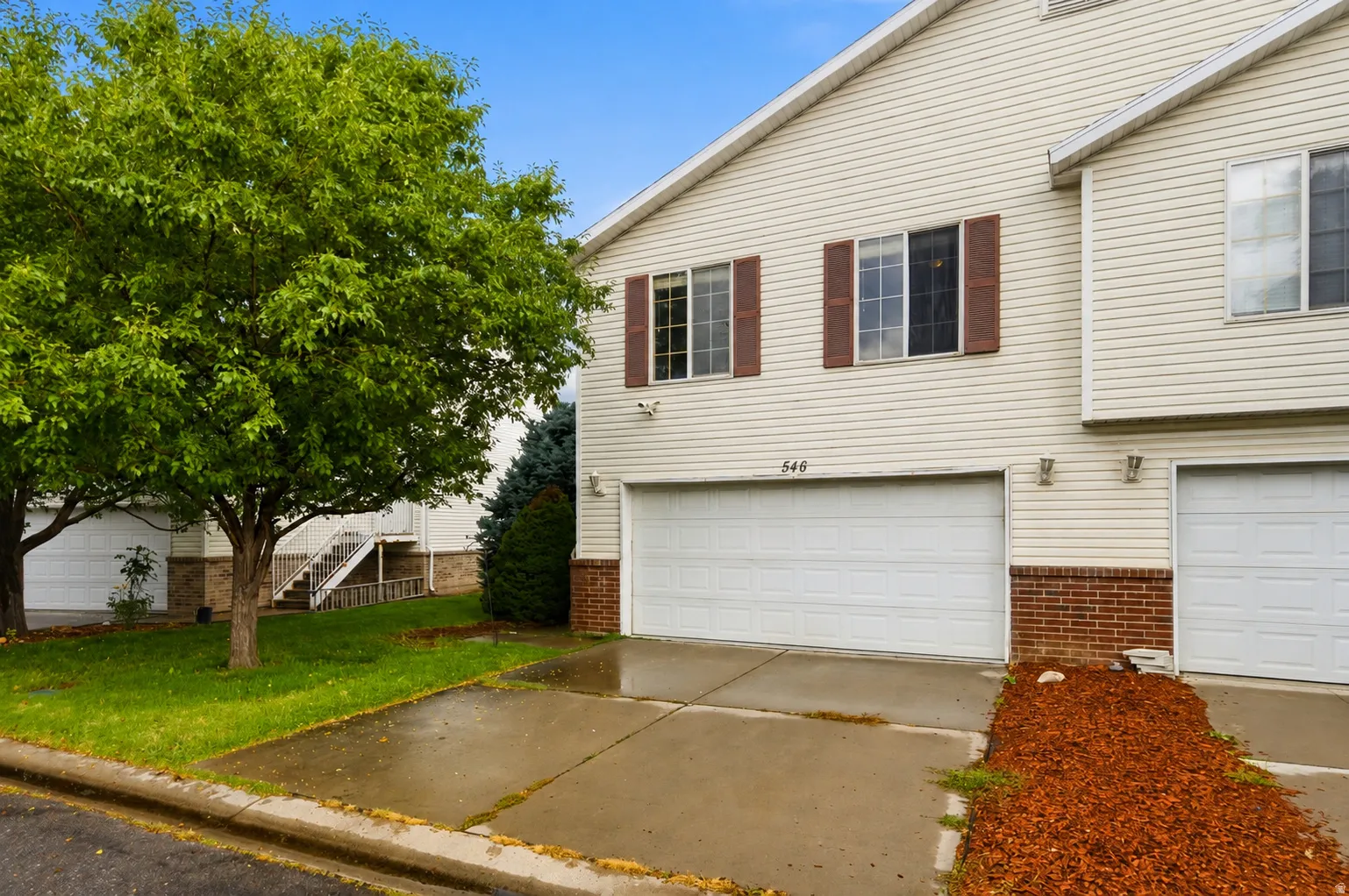 Cream-colored siding with a brick facade and brown shutters