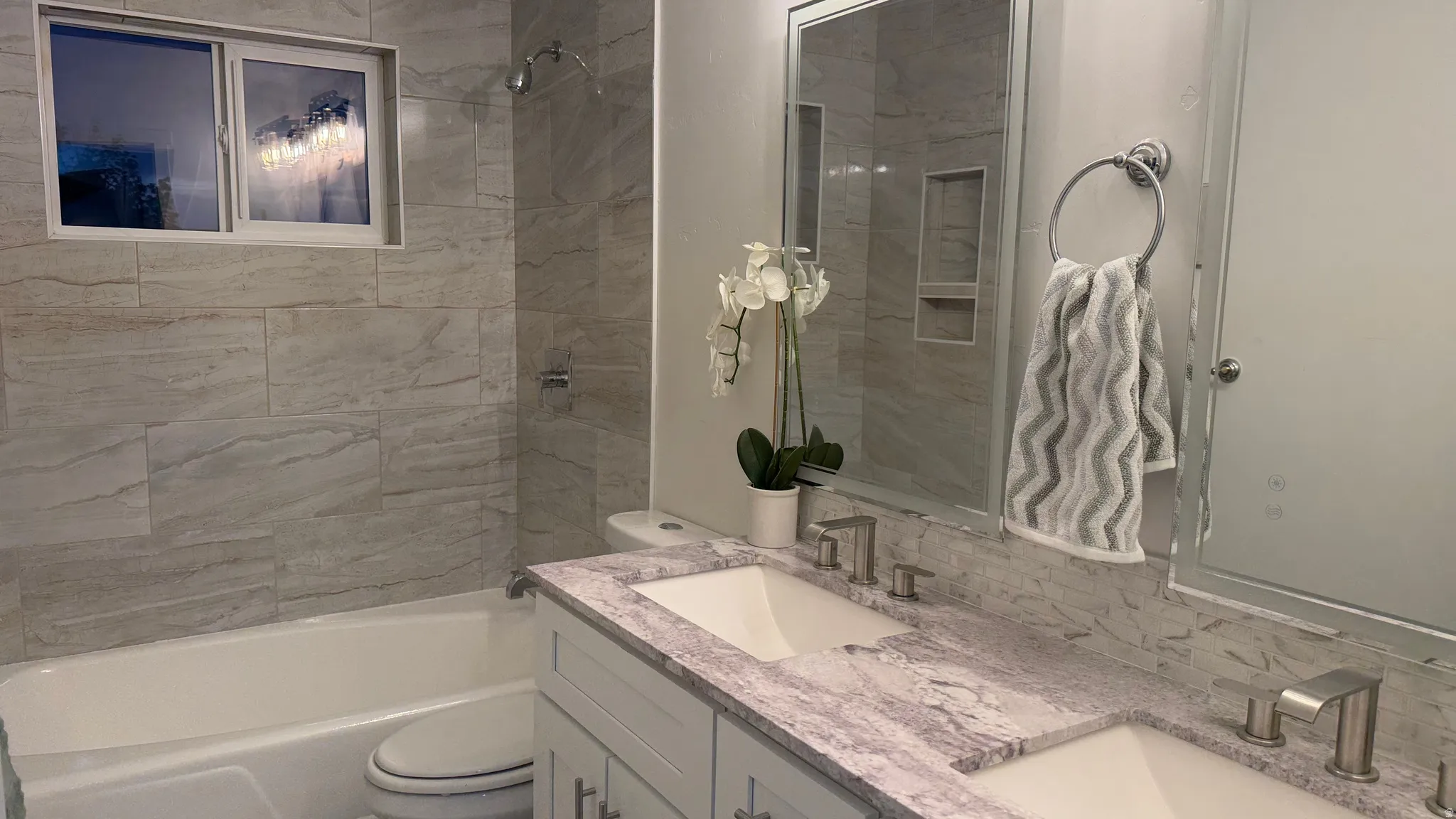 Spa-inspired bathroom featuring a marble-look quartz countertop, dual vanity with brushed nickel fixtures, and large framed mirror
