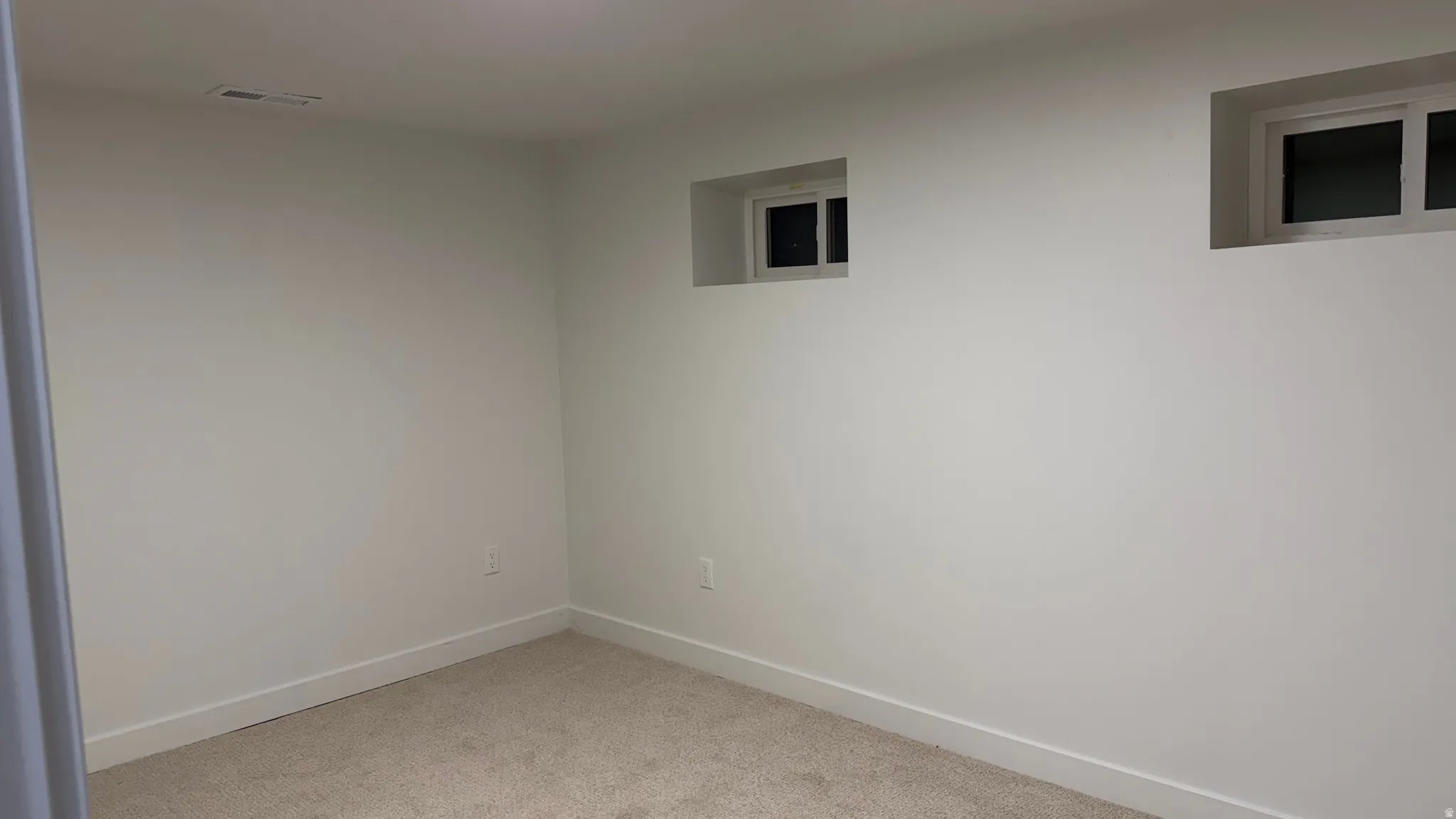 Crisp white walls, two recessed windows, and neutral carpeting