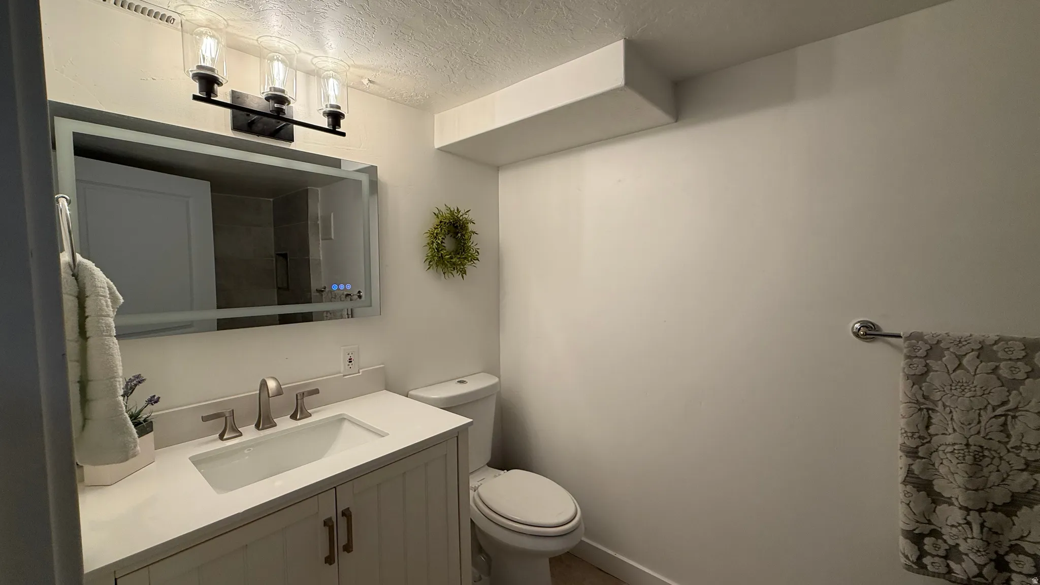 White vanity with cabinet storage, integrated rectangular sink, and light-toned countertop